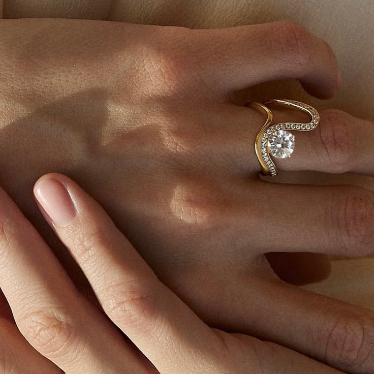 a woman's hand with two different rings on her left and the other hand holding an engagement ring