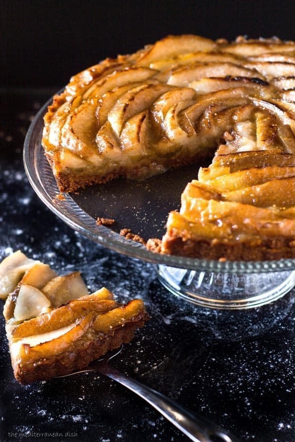 a pie with slices taken out of it on a glass platter next to another pie