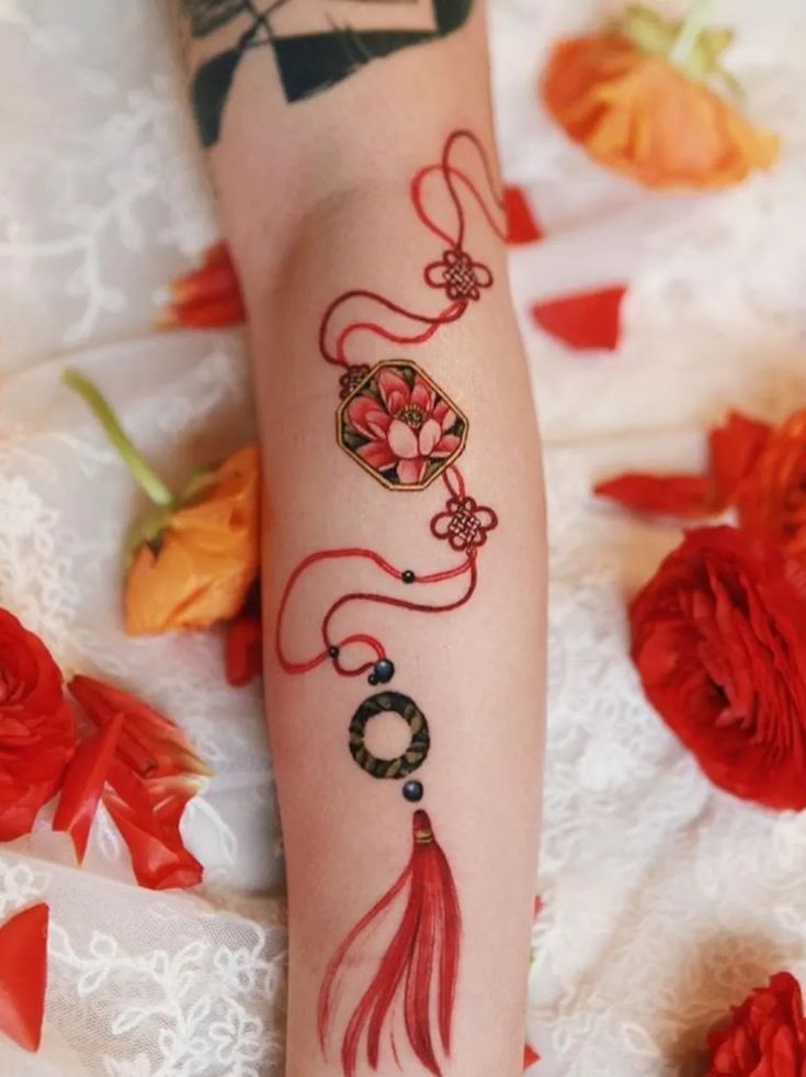 a woman's arm with tattoos on it and flowers scattered around the area behind her