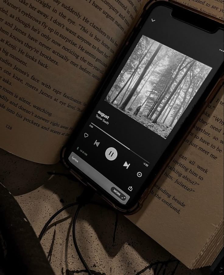 an open book sitting on top of a table next to a cell phone and pencil