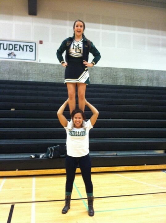 two cheerleaders are doing tricks on the basketball court