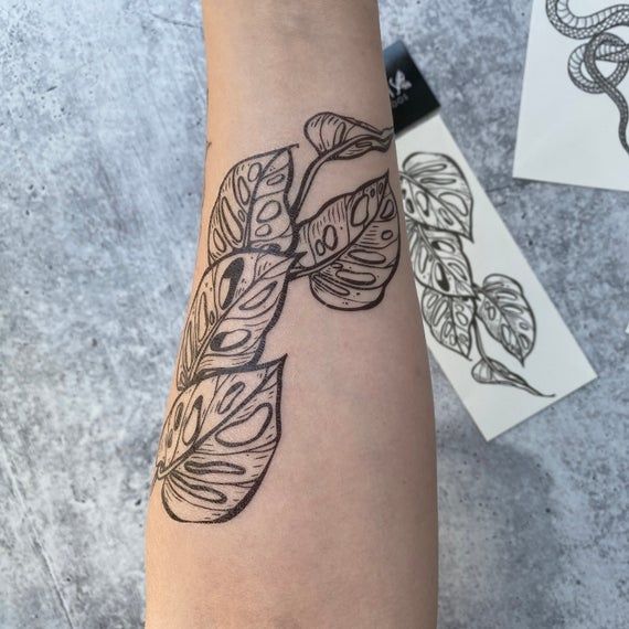 a woman's arm with a tattoo on it and leaves around the wrist area