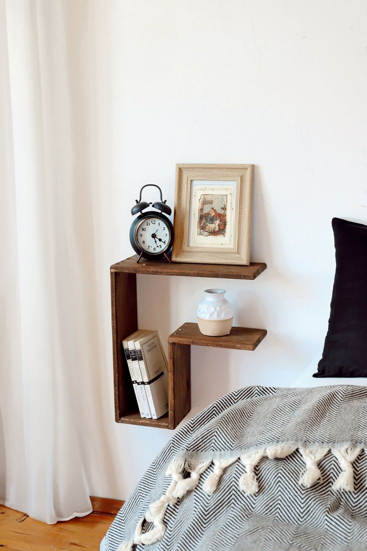 a bed room with a neatly made bed and two shelves on the wall above it