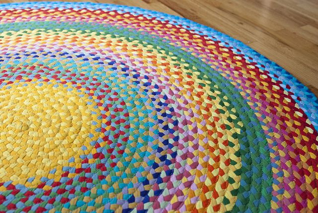 a multicolored round rug on the floor with wood floors in the back ground