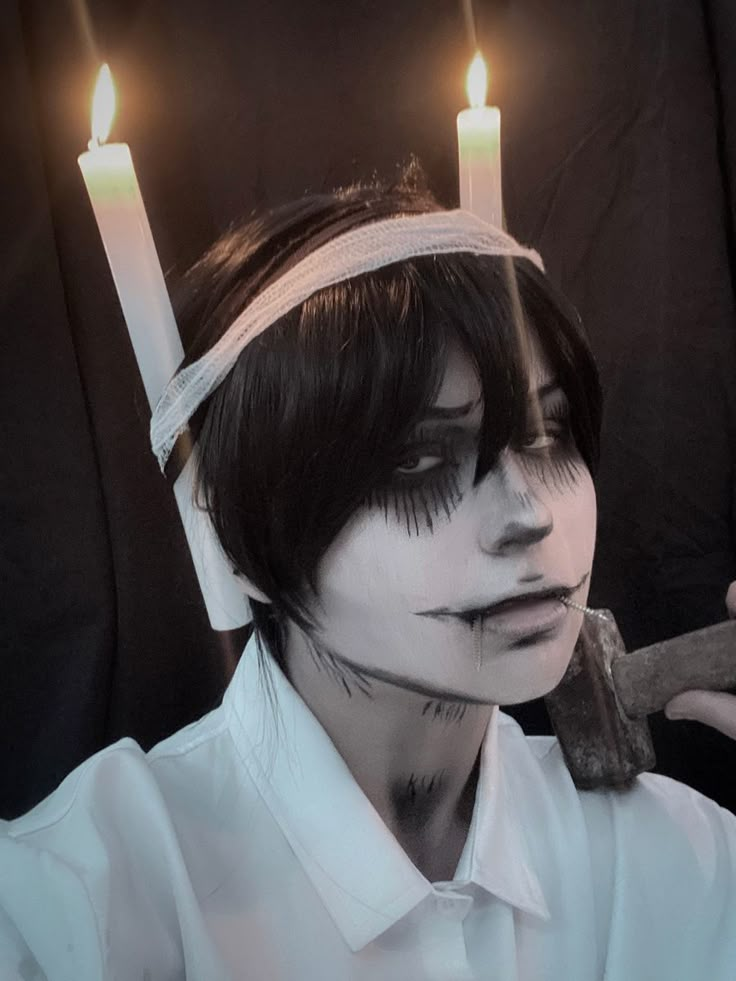 a man with white makeup and candles on his head is holding a pair of scissors