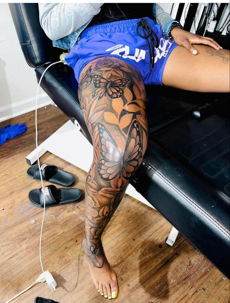 a person with tattoos on their legs sitting in front of a computer keyboard and headphones