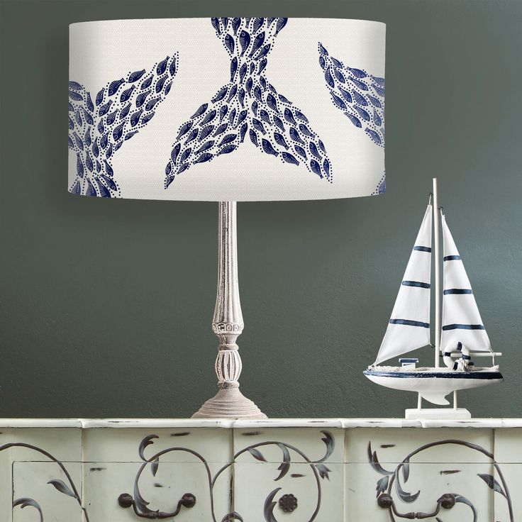 a lamp that is sitting on top of a dresser next to a sailboat figurine