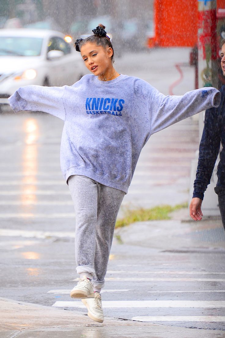 a woman is walking down the street in the rain with her arms spread out and feet stretched out