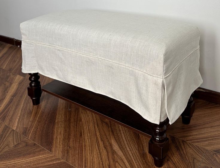 a white ottoman sitting on top of a hard wood floor