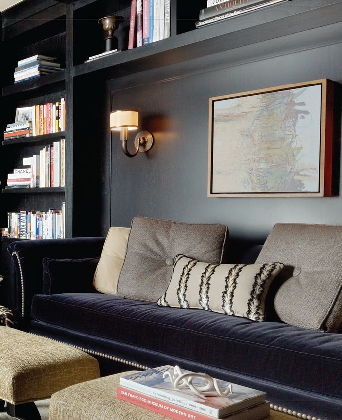 a living room filled with furniture and bookshelves next to a wall full of books