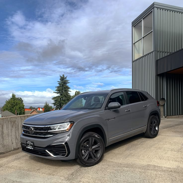 a grey volkswagen suv parked in front of a building with a metal structure behind it