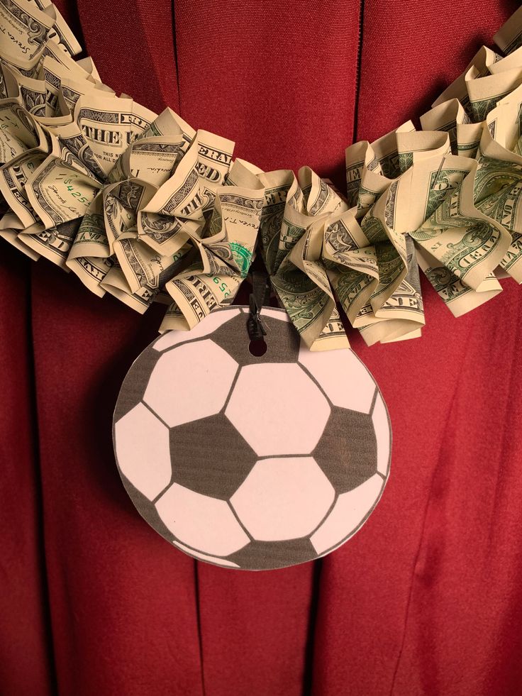 a soccer ball is hanging from a necklace made out of dollar bills on a red background