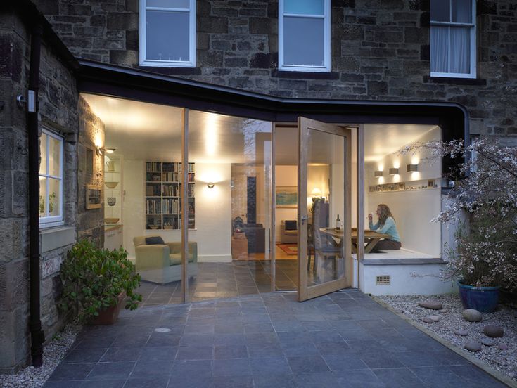 a person sitting in the doorway of a house at night with their reflection on the glass door