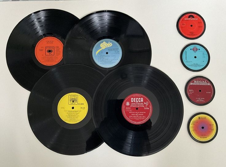 several different colored records on a white wall