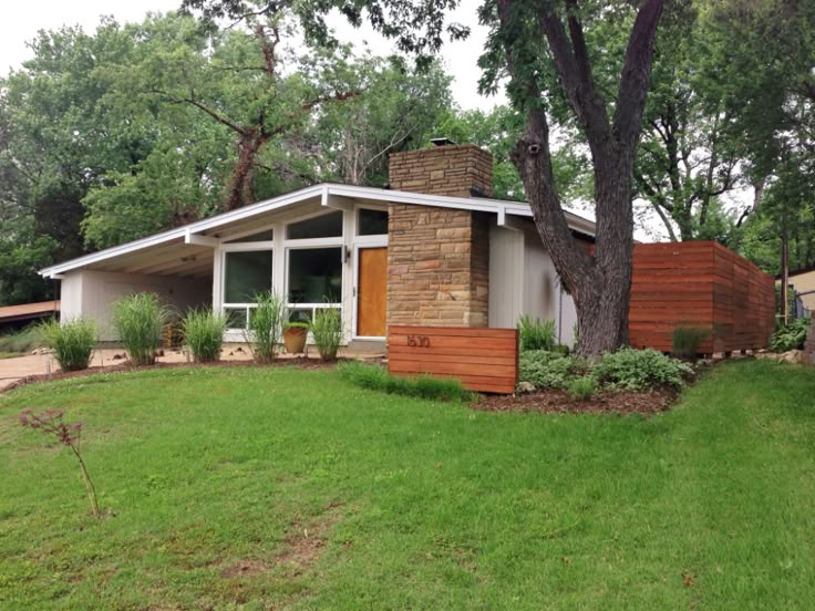 a small house sitting on top of a lush green field next to a tree and grass covered yard