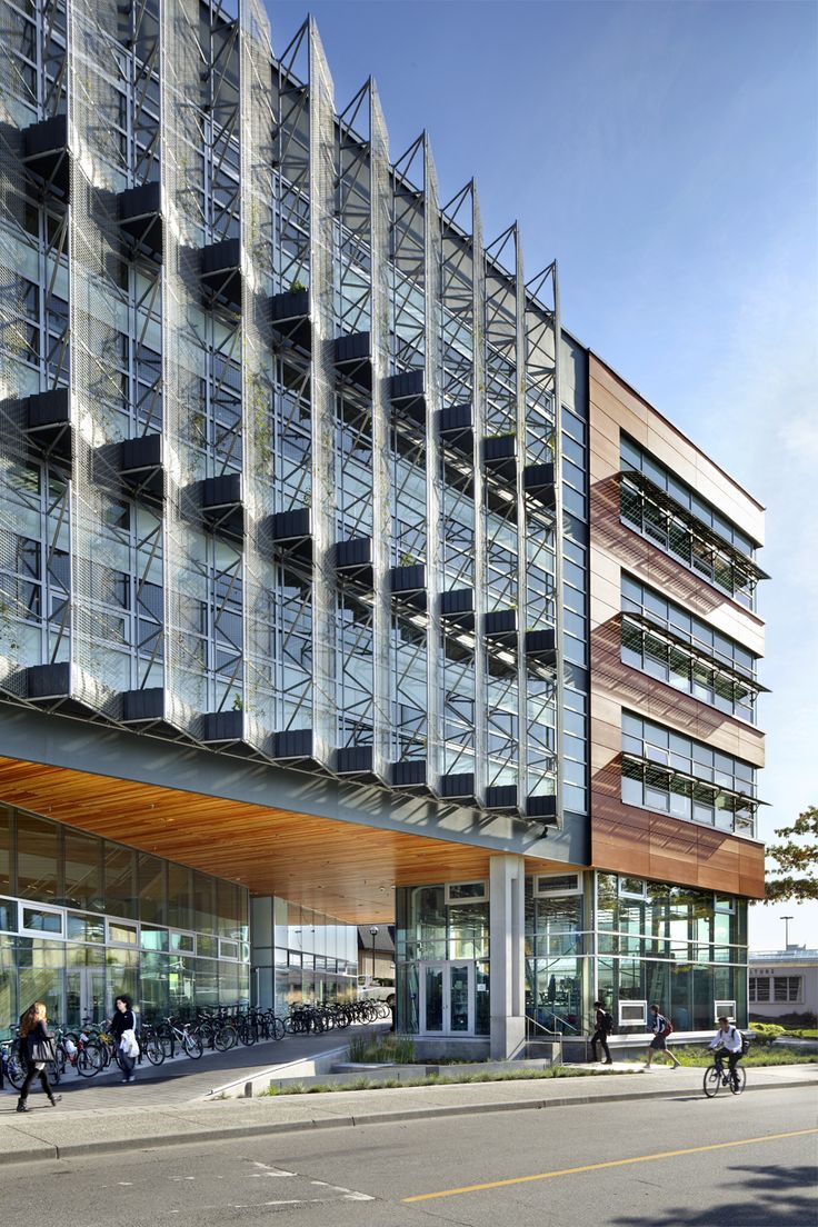 a large building with many windows and people walking around the outside area on bikes parked in front of it