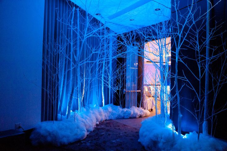 the room is decorated with blue lights and white fur on the floor, along with trees