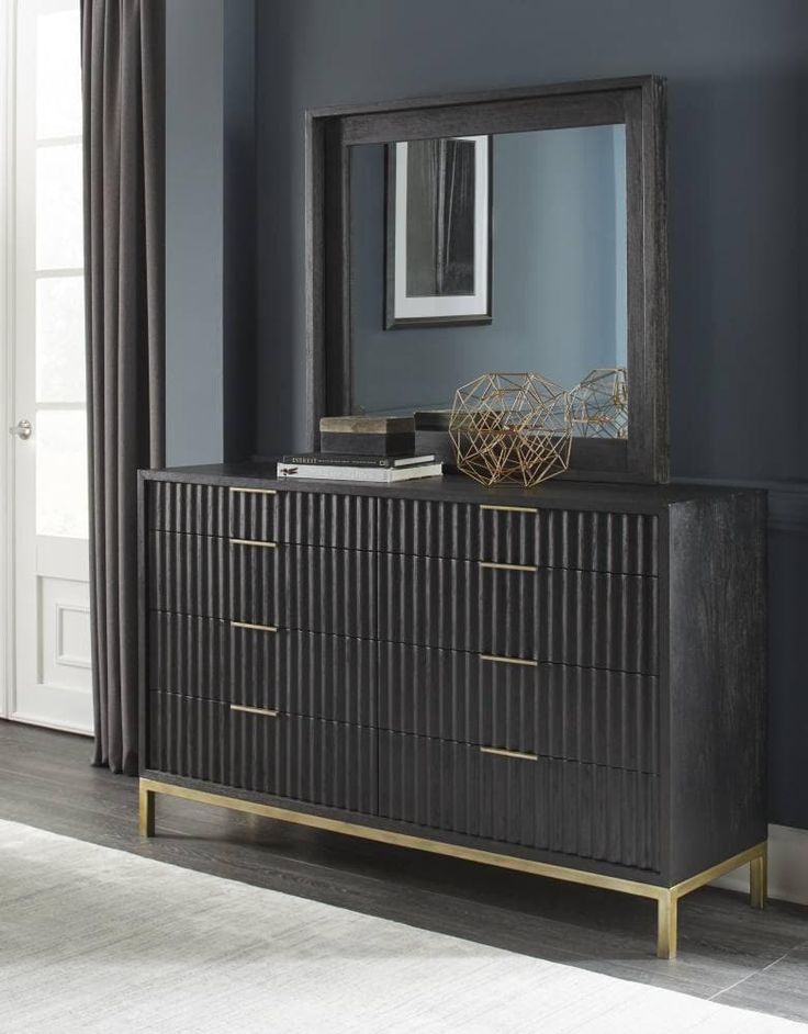 a black and gold dresser with a mirror on it's sideboard in front of a blue wall