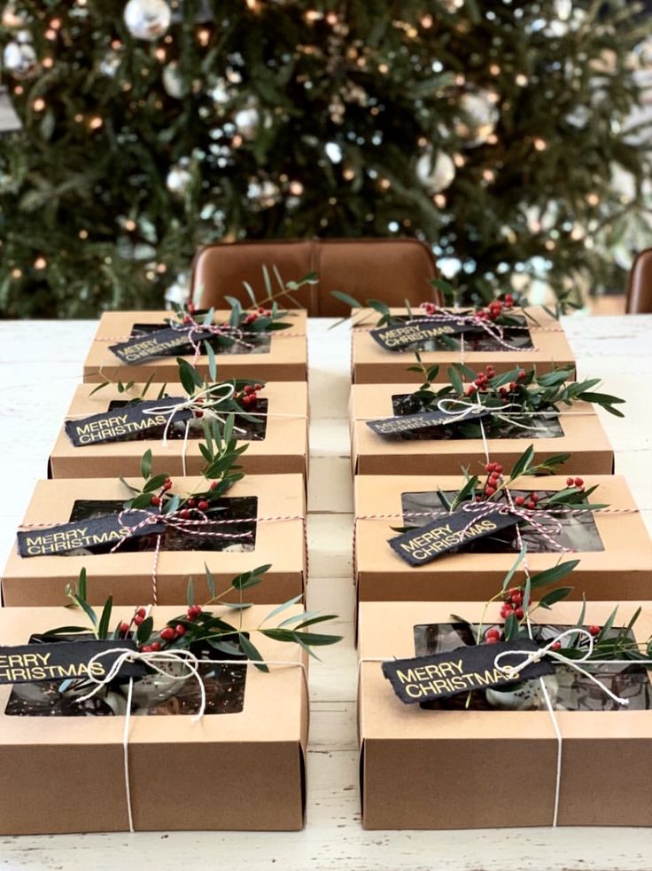 several boxes are wrapped in brown paper and tied with twine ribbons, sitting on a table next to a christmas tree