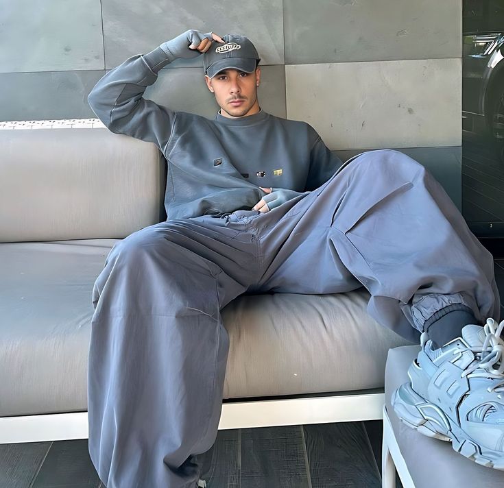 a man sitting on top of a couch next to a blue shoe and wearing a hat