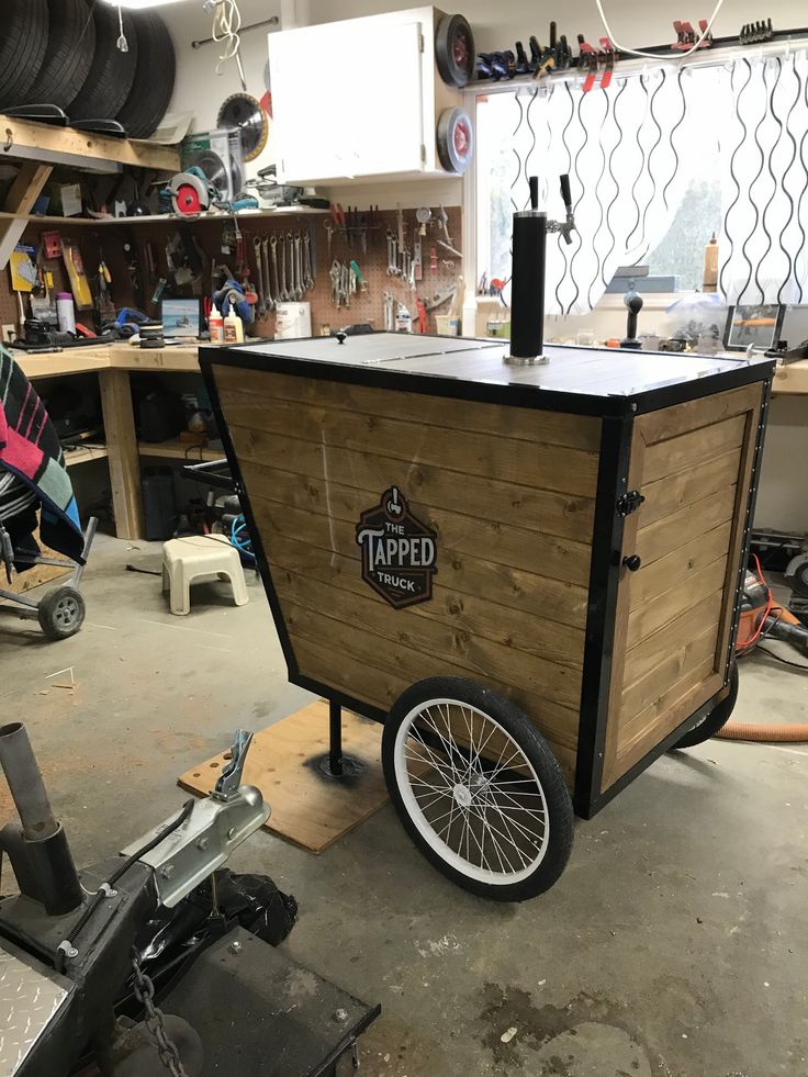 a small cart made out of wood with wheels attached to it in a workshop area