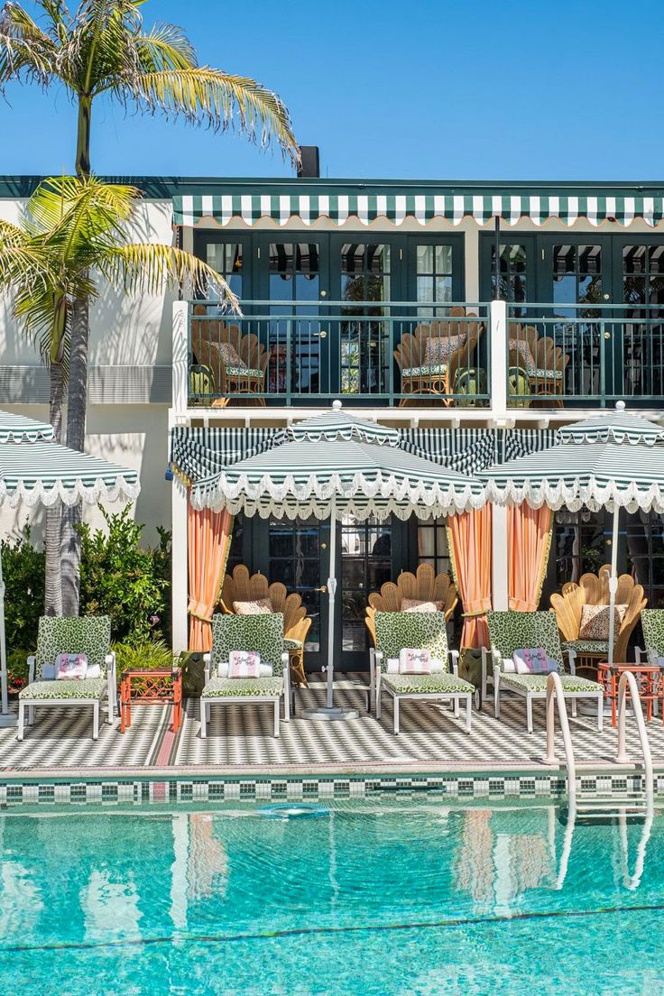 an outdoor swimming pool with chairs and umbrellas next to the side of a building