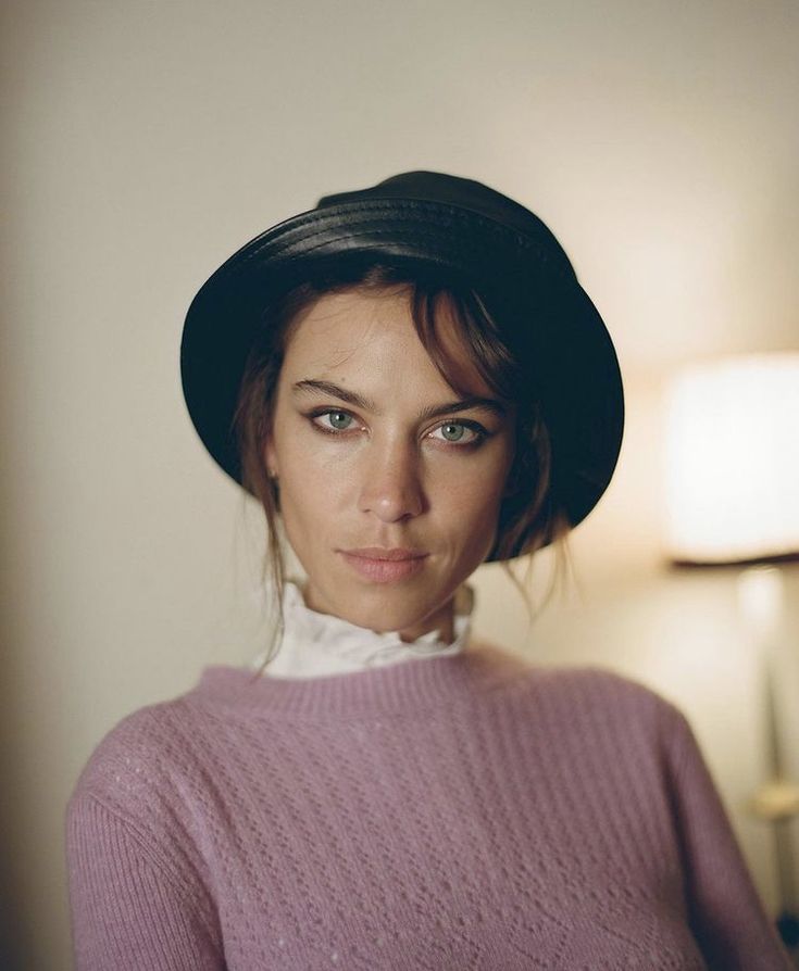 a woman wearing a pink sweater and black hat