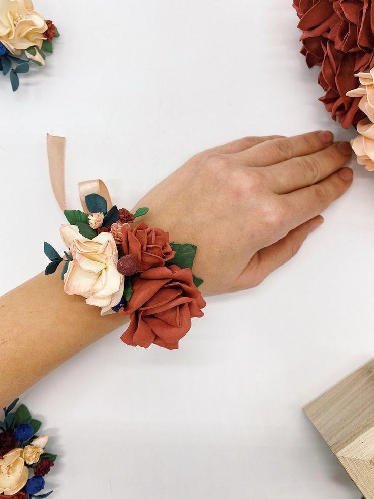 a woman's hand is shown with flowers on her wrist and the other hand has a ribbon around it