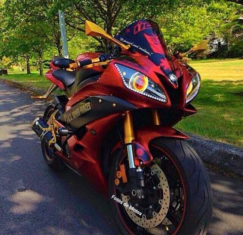 a red motorcycle parked on the side of a road next to a tree filled park