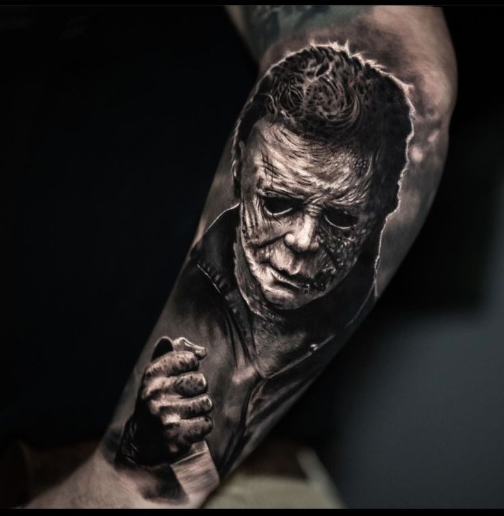 a man's arm with a black and white tattoo of a scary character holding a knife