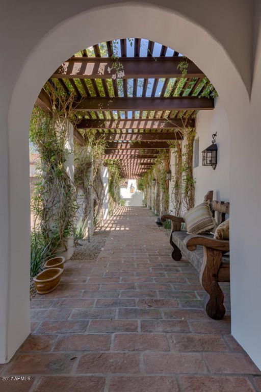 an arched walkway with benches and potted plants