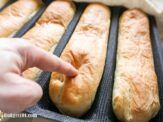 a person pointing at some breads on a grill