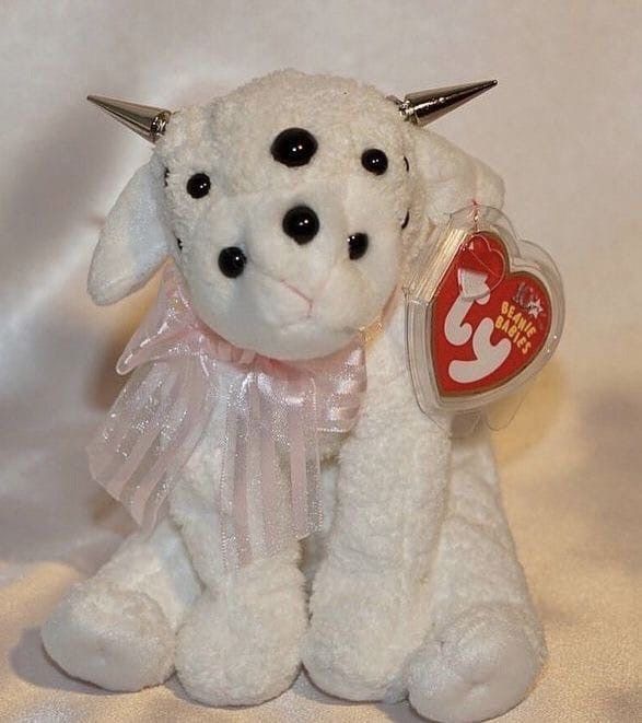 a white stuffed animal with horns and a tag on it's ear, sitting against a white background