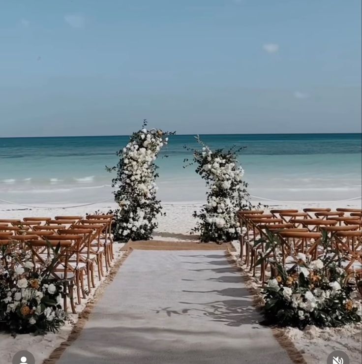 an outdoor ceremony set up on the beach with chairs and flowers in front of the ocean