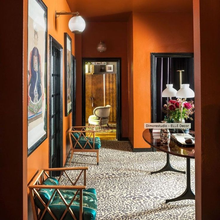 an orange hallway with chairs, tables and pictures on the wall in front of them