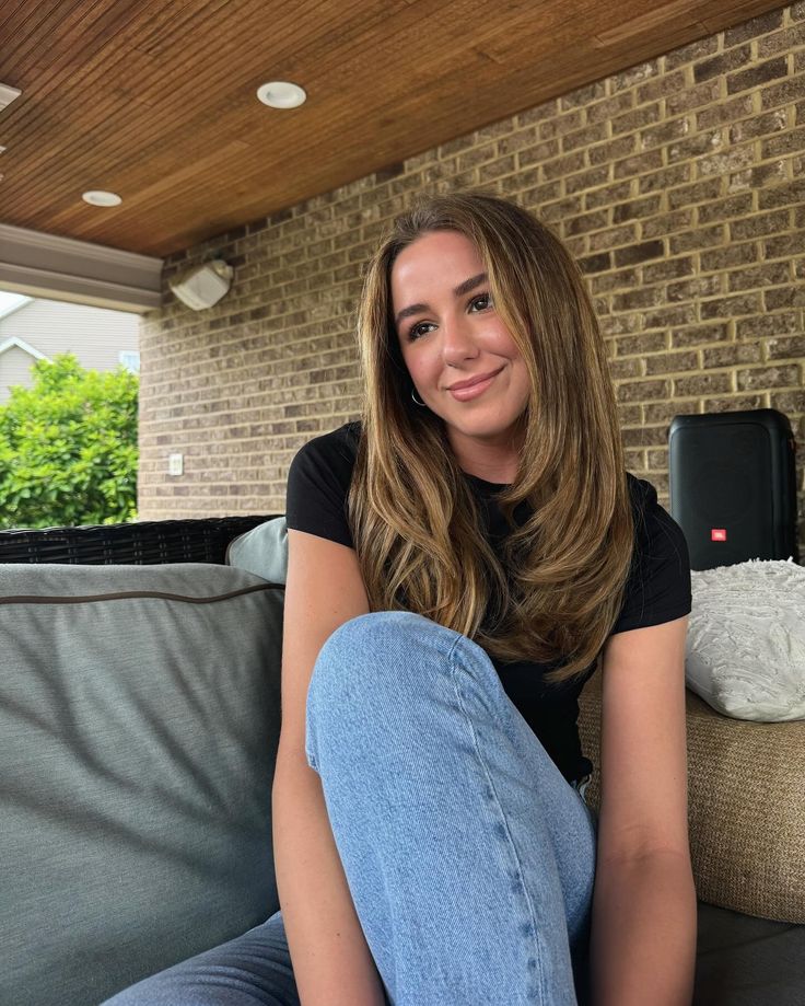 a woman sitting on top of a couch in front of a brick wall and ceiling