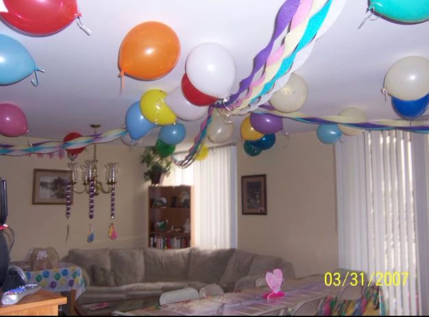 balloons and streamers are hanging from the ceiling in a living room with couches