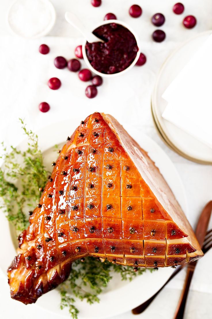 a piece of meat with cranberry sauce on it sitting on a plate next to silverware