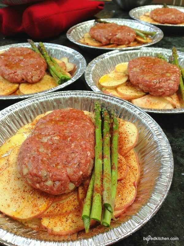 asparagus, potatoes and hamburgers on tin foil are ready to be served