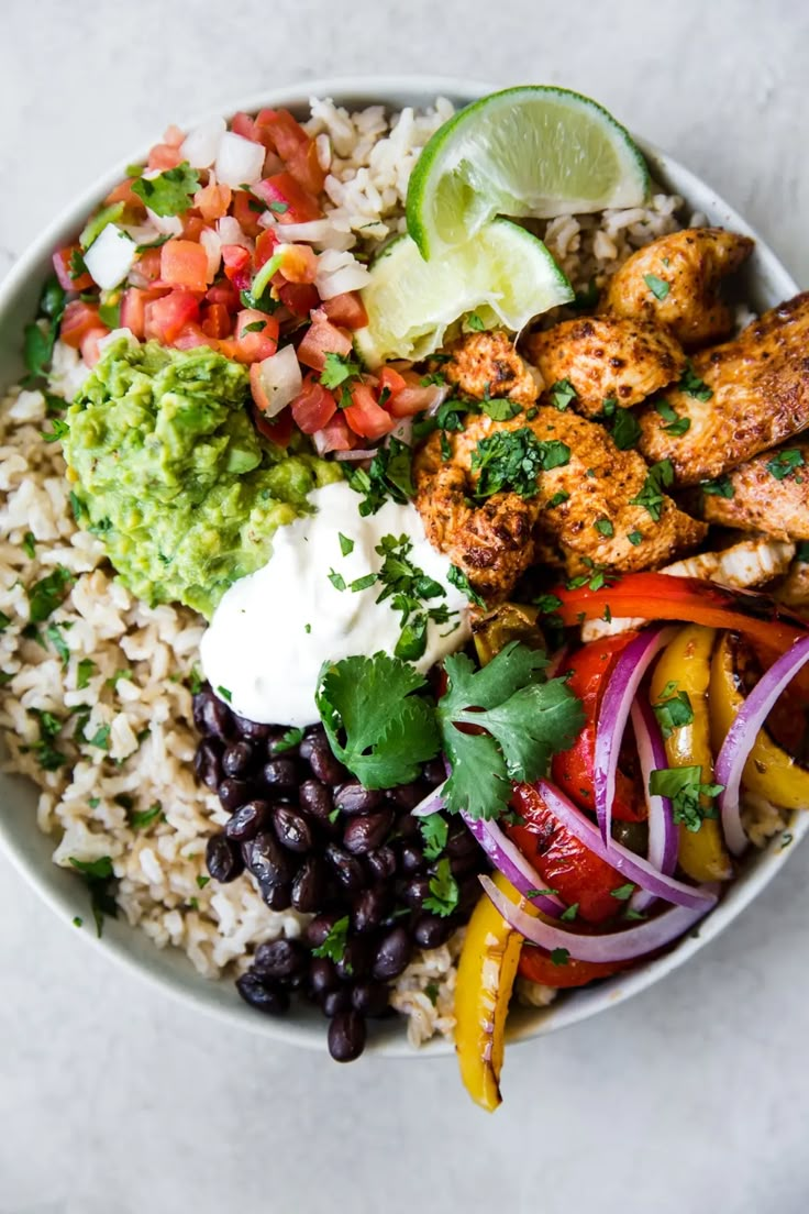 a white bowl filled with rice, meat and veggies on top of it