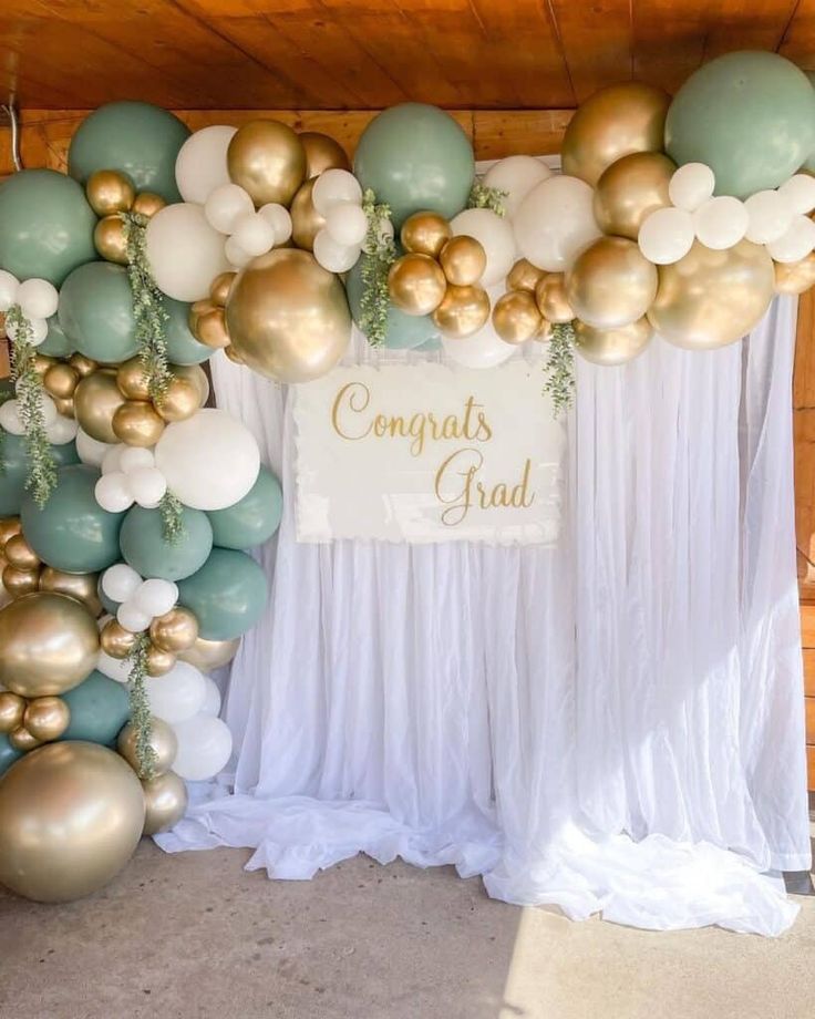 balloons and greenery decorate the backdrop for a congrats grad party