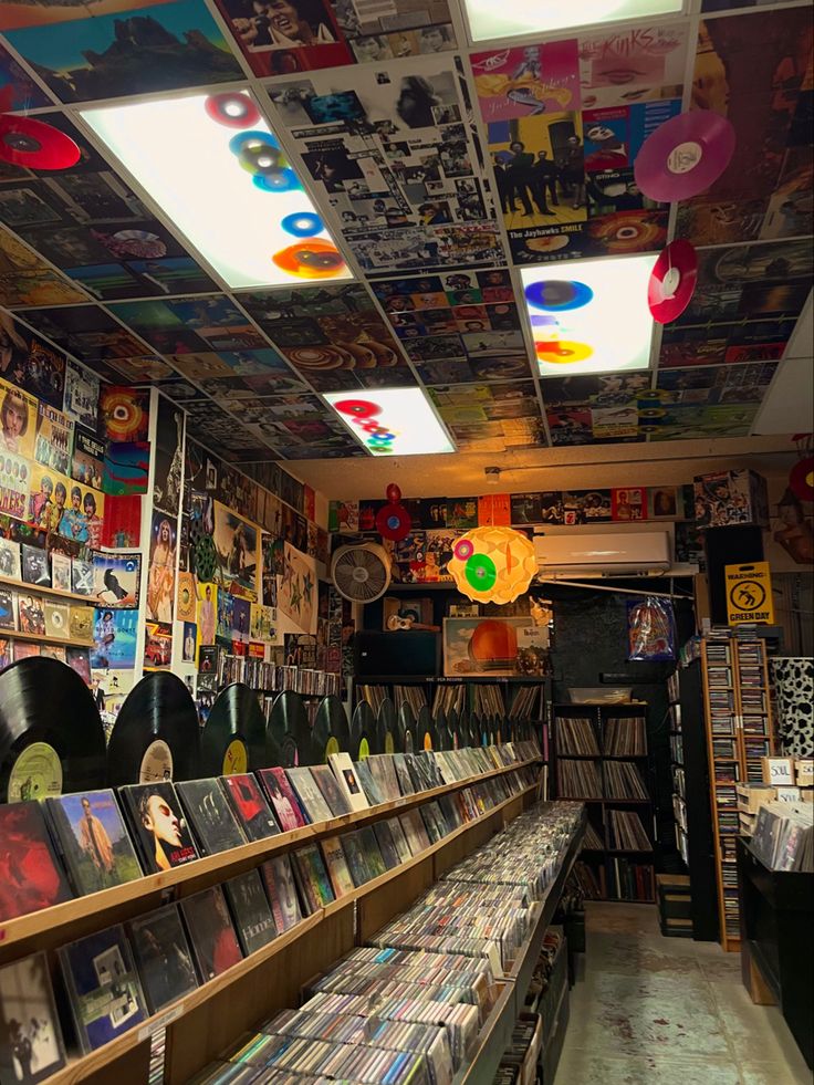 the inside of a record store with many records on shelves and vinyls hanging from the ceiling