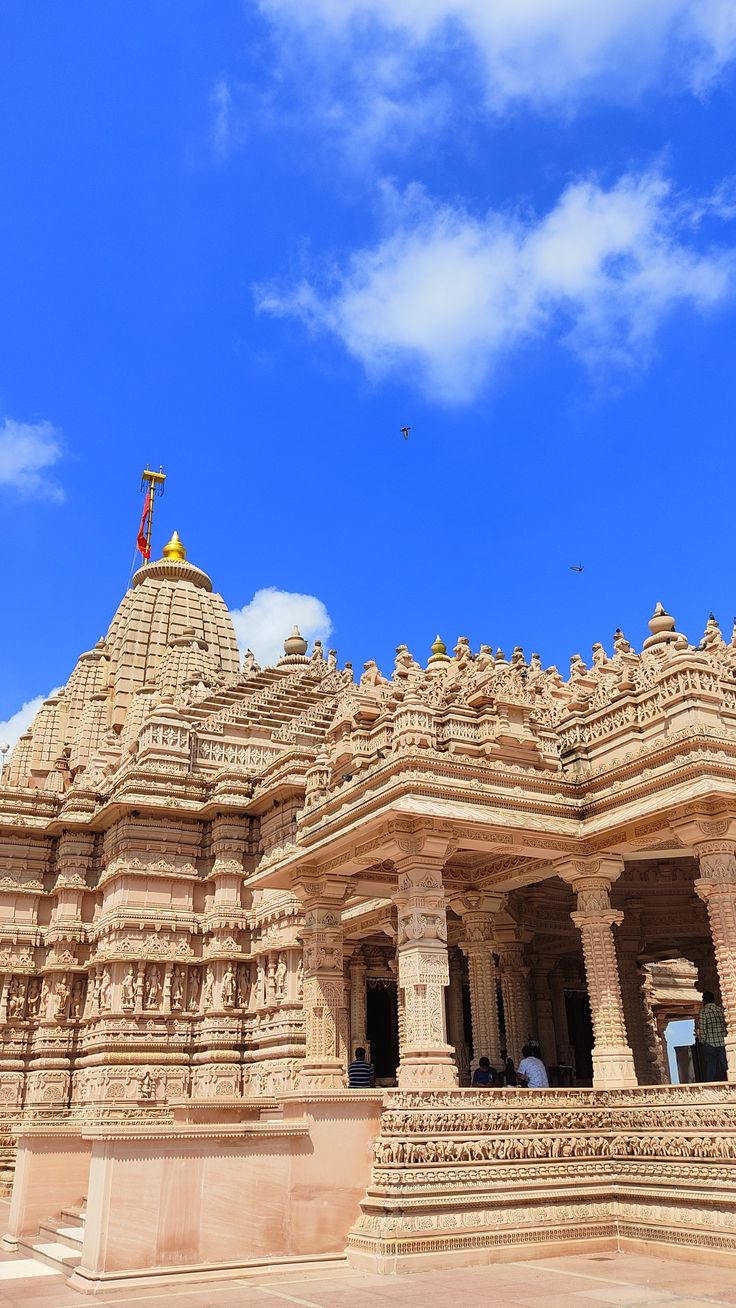 an ornately carved building with blue skies in the background and clouds in the sky