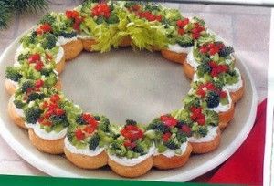 a christmas wreath shaped cake on a white platter with red and green toppings