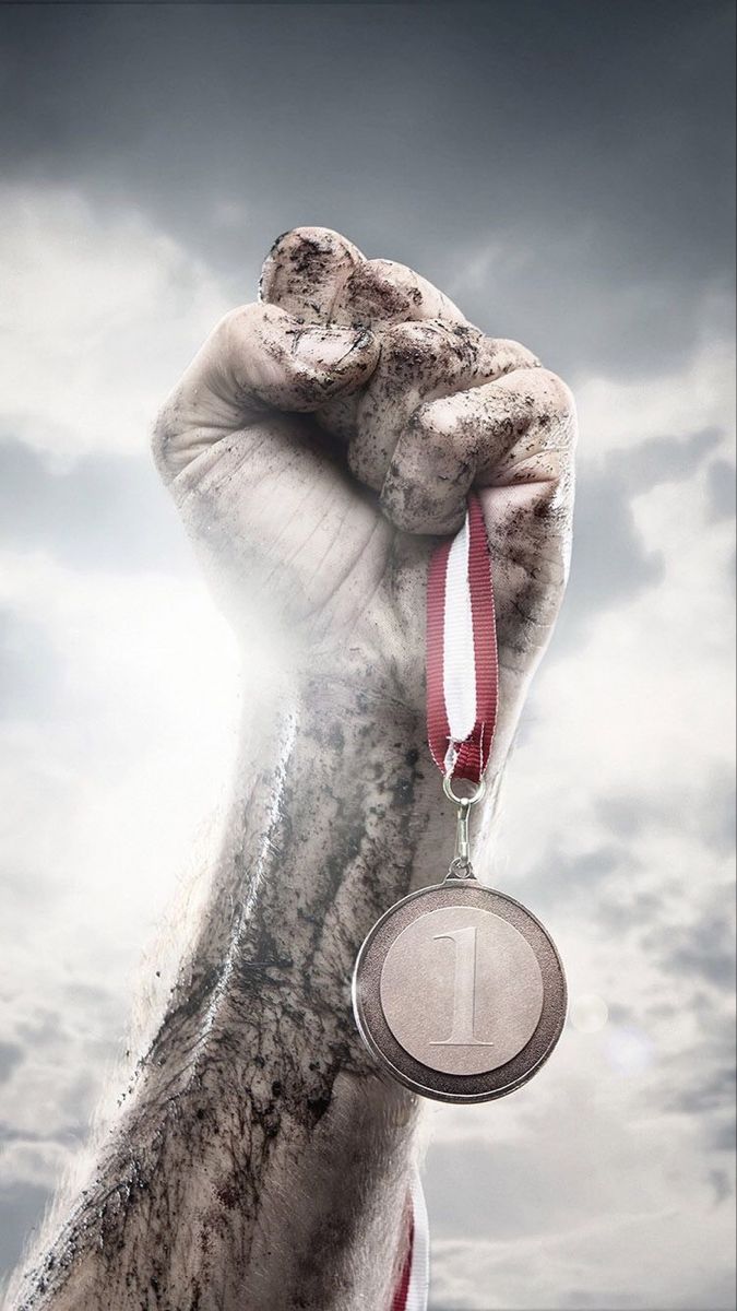 a hand holding a medal in front of a cloudy sky