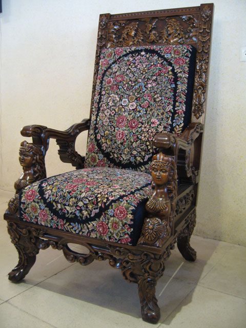 an ornately decorated chair sitting on top of a tile floor next to a wall