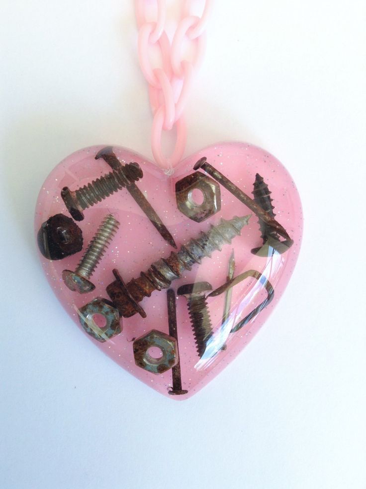 a pink heart with screws and nails attached to it