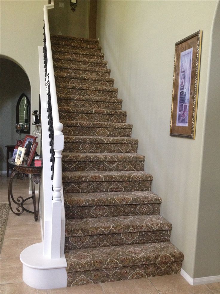 there is a stair case on the wall next to the carpeted stairs in this house