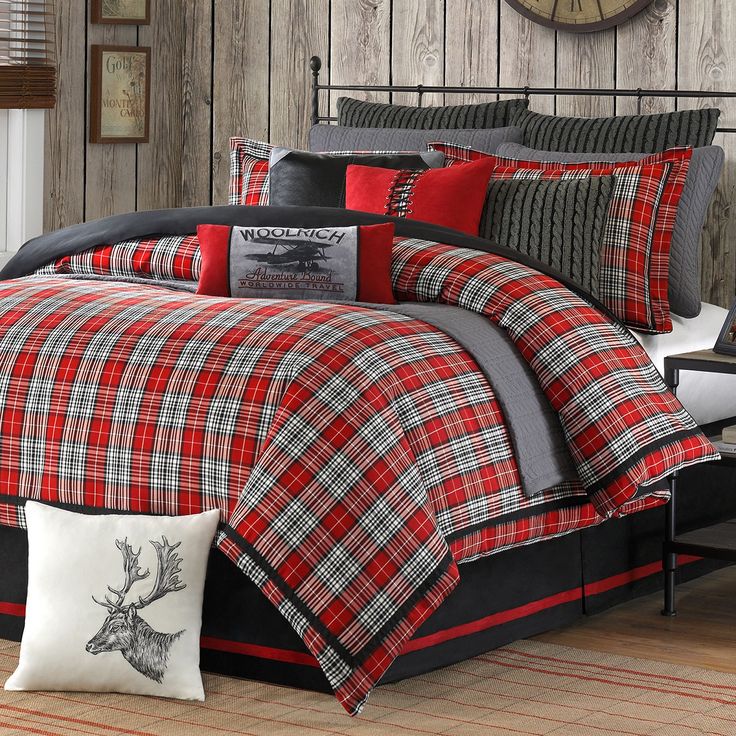 a red and black plaid comforter set with deer head on the pillow, in front of a wooden paneled wall