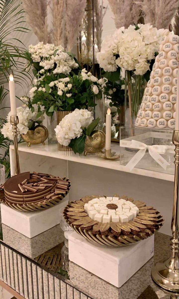 three desserts sitting on top of a table next to candles and vases filled with flowers